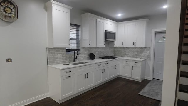 kitchen featuring dark wood finished floors, stainless steel microwave, white cabinets, and a sink