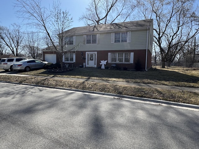 view of front of home with a front yard, fence, driveway, a garage, and brick siding