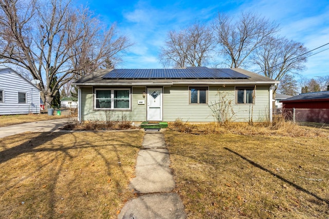 view of front of home featuring solar panels, a front lawn, and fence