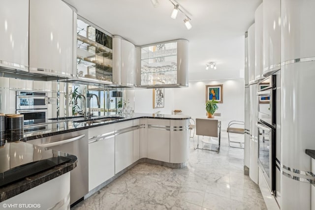 kitchen with marble finish floor, a sink, dark stone counters, appliances with stainless steel finishes, and white cabinets