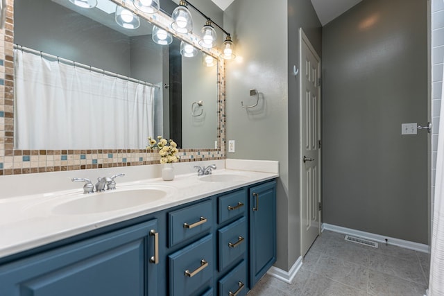 bathroom with tile patterned floors, double vanity, a sink, and baseboards