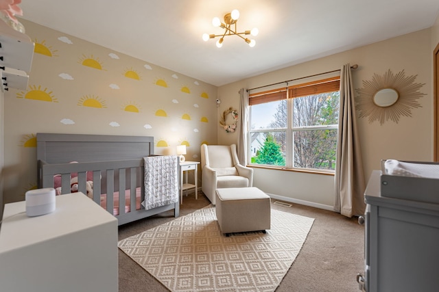carpeted bedroom featuring a notable chandelier, a crib, visible vents, baseboards, and wallpapered walls