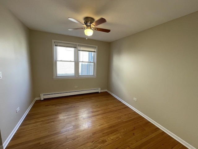 unfurnished room with a baseboard heating unit, baseboards, wood finished floors, and a ceiling fan