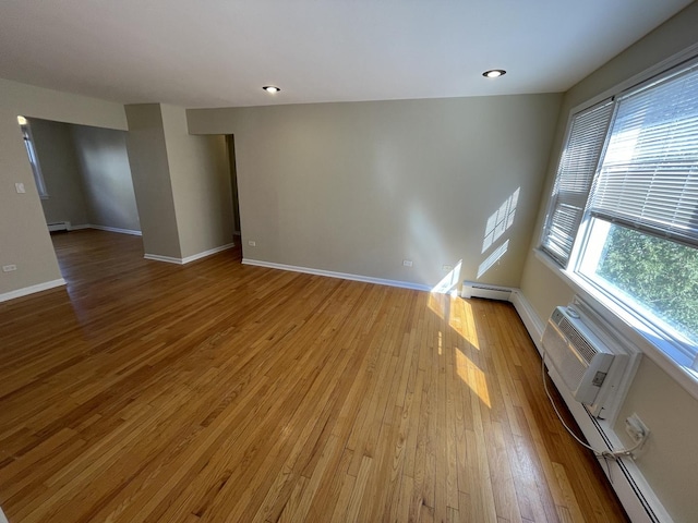 spare room featuring light wood finished floors, baseboards, baseboard heating, recessed lighting, and a baseboard radiator