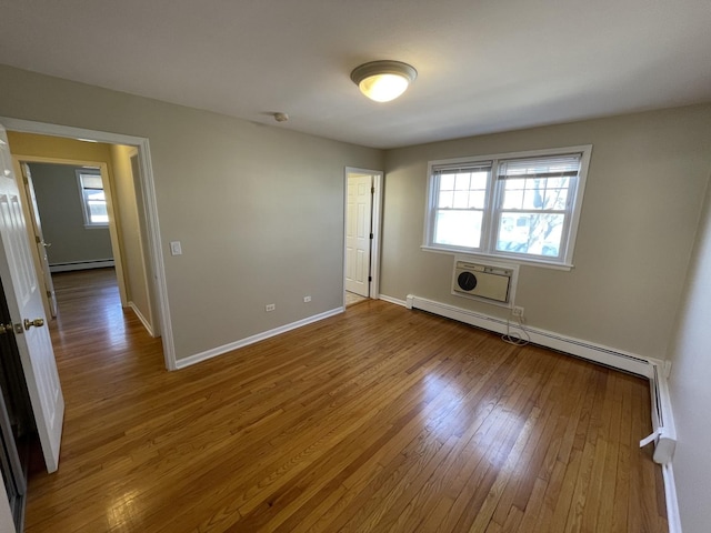 unfurnished bedroom featuring hardwood / wood-style flooring, baseboards, and a baseboard radiator