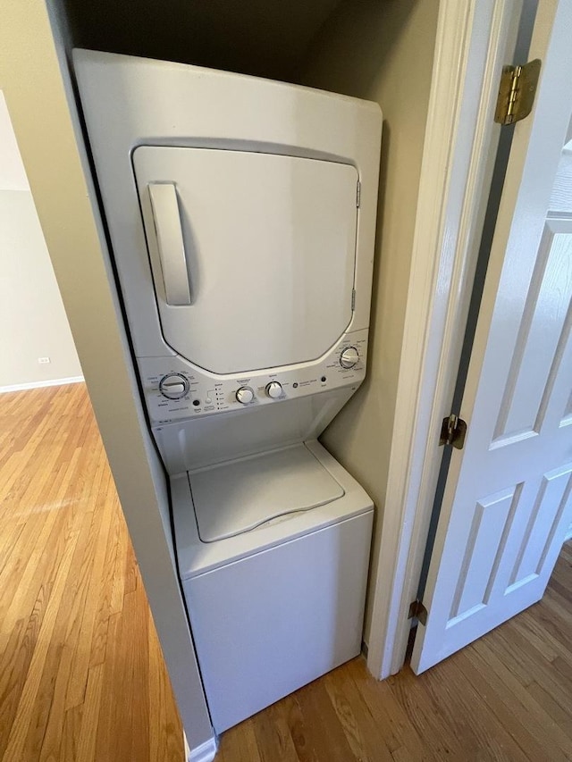 washroom with stacked washer / dryer, laundry area, and wood finished floors