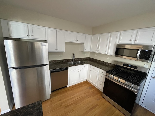 kitchen featuring a sink, white cabinets, light wood finished floors, and stainless steel appliances