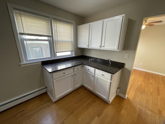 kitchen featuring baseboards, light wood-style flooring, ceiling fan, white cabinets, and baseboard heating