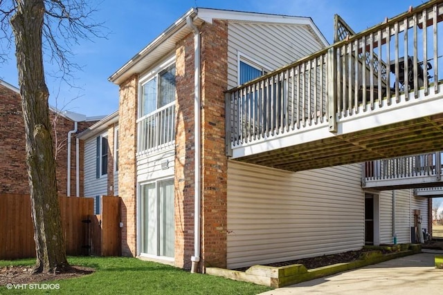 view of property exterior featuring brick siding and fence