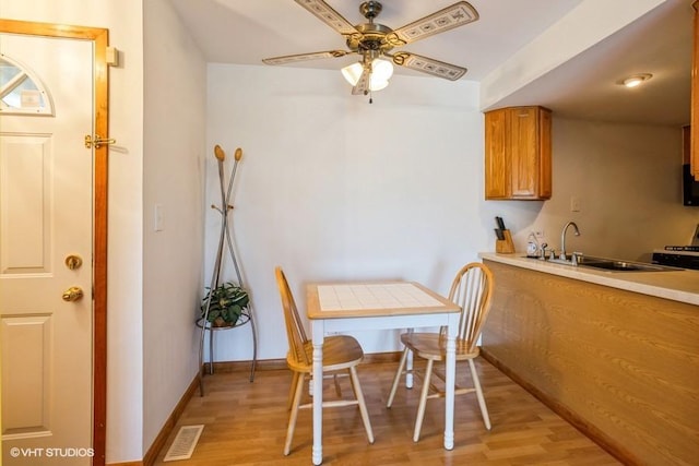 dining room with light wood finished floors, visible vents, baseboards, and a ceiling fan