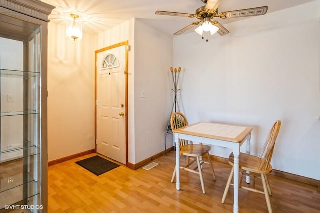 dining room featuring light wood-type flooring, baseboards, visible vents, and a ceiling fan