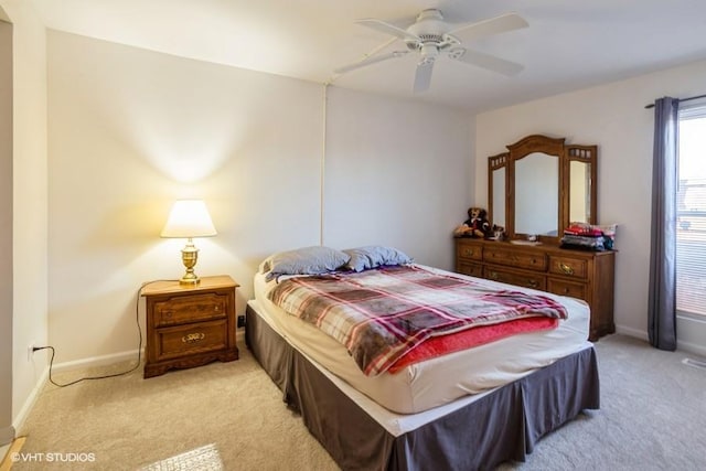 bedroom featuring light colored carpet, a ceiling fan, and baseboards