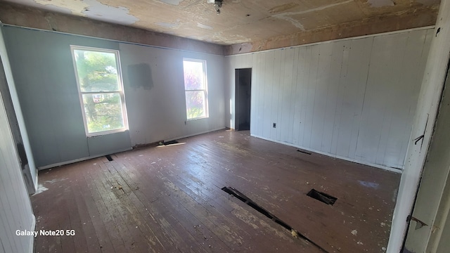 809 W Columbia St, Danville, IL 61832 - spare room featuring hardwood / wood-style flooring, baseboards, visible vents, and wood walls