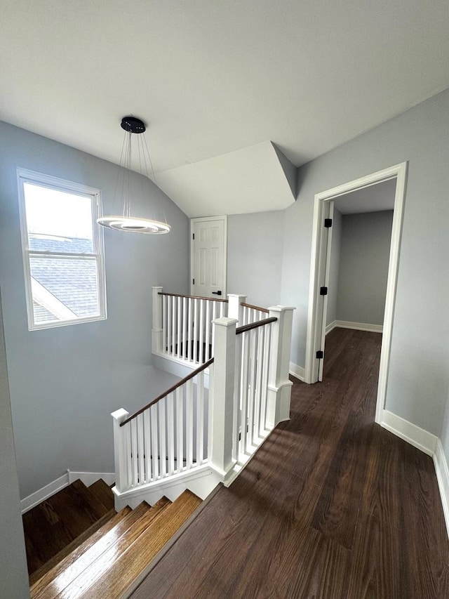 hall featuring wood finished floors, an upstairs landing, baseboards, and vaulted ceiling