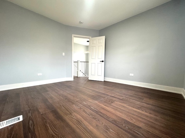 spare room with visible vents, baseboards, and dark wood finished floors