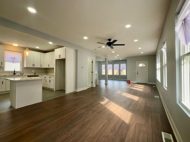 unfurnished living room featuring visible vents, dark wood-type flooring, a ceiling fan, recessed lighting, and baseboards