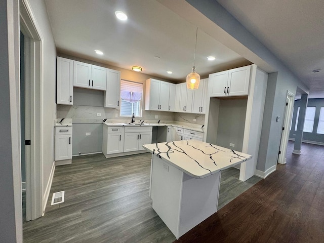 kitchen with dark wood-style floors, visible vents, white cabinets, and a kitchen island