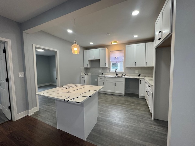 kitchen with dark wood finished floors, a center island, recessed lighting, white cabinets, and baseboards