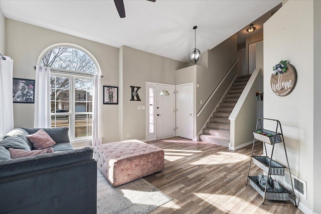 foyer with visible vents, a ceiling fan, wood finished floors, baseboards, and stairs