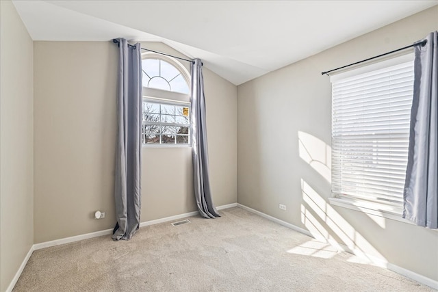 carpeted spare room featuring visible vents, lofted ceiling, and baseboards