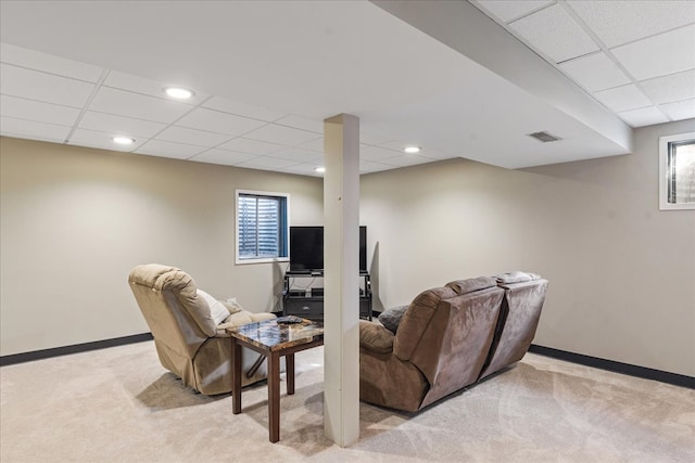 living area featuring a drop ceiling, visible vents, light carpet, and baseboards