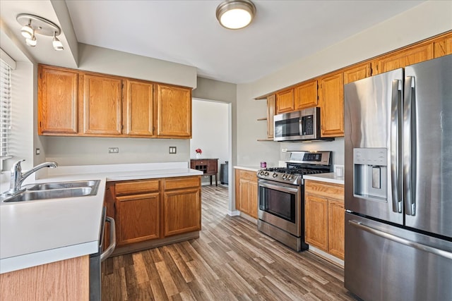 kitchen featuring a sink, appliances with stainless steel finishes, dark wood-style floors, and light countertops