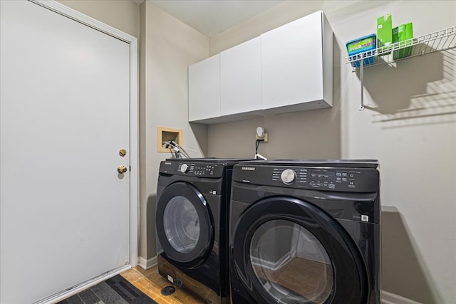 clothes washing area with baseboards, cabinet space, and separate washer and dryer