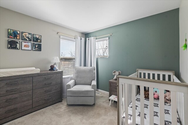 carpeted bedroom with a crib and baseboards