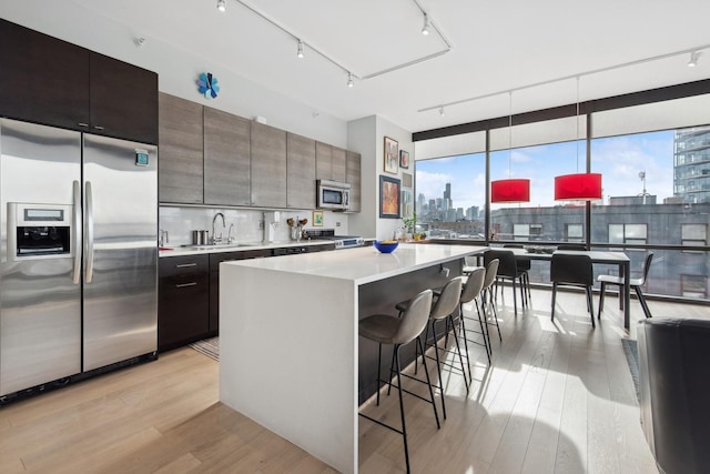 kitchen with a city view, light wood-style flooring, stainless steel appliances, and a kitchen bar