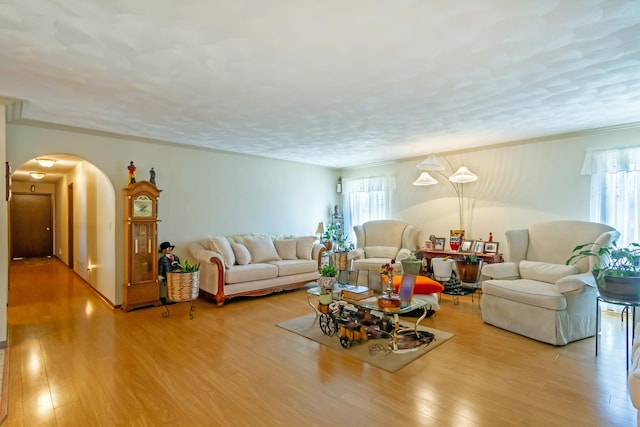 living room featuring wood finished floors, arched walkways, and a textured ceiling