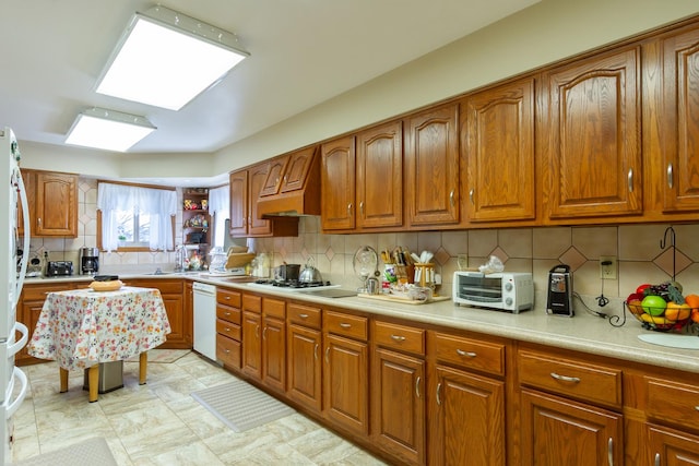 kitchen with white appliances, a toaster, decorative backsplash, light countertops, and brown cabinets