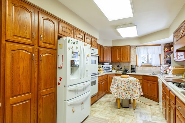 kitchen with a sink, brown cabinets, and white fridge with ice dispenser