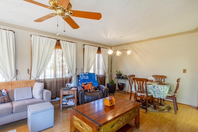 living area featuring a ceiling fan, baseboards, light wood finished floors, and ornamental molding