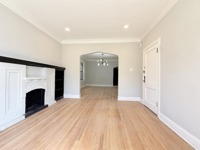 unfurnished living room with baseboards, light wood-style flooring, arched walkways, ornamental molding, and a chandelier