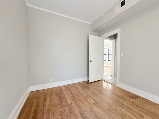 spare room featuring visible vents, baseboards, crown molding, and light wood-style floors