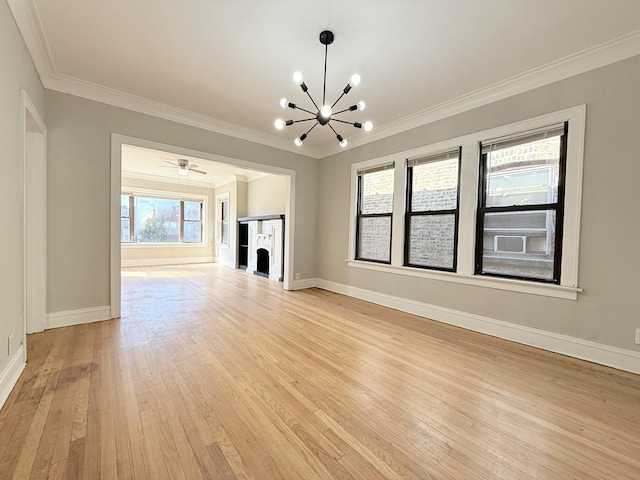 unfurnished living room featuring a notable chandelier, light wood-style floors, a fireplace, crown molding, and baseboards