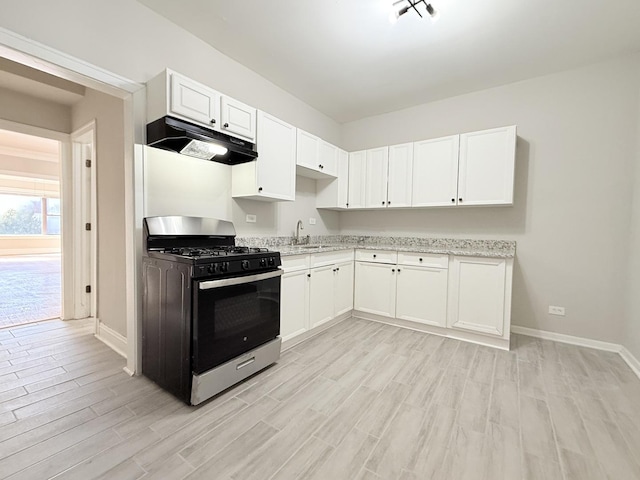 kitchen featuring under cabinet range hood, white cabinets, gas stove, and a sink