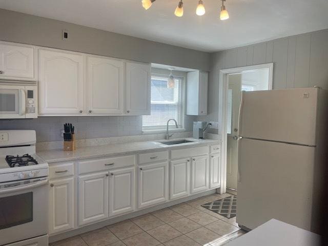 kitchen with white cabinetry, white appliances, and a sink