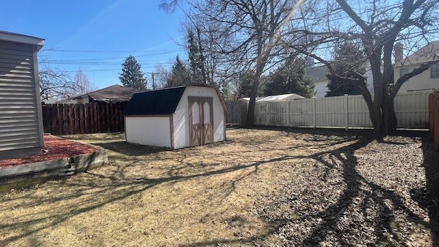 view of yard featuring a storage shed, a fenced backyard, and an outdoor structure