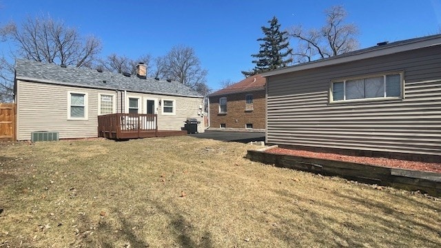 rear view of property featuring a deck, cooling unit, and a yard