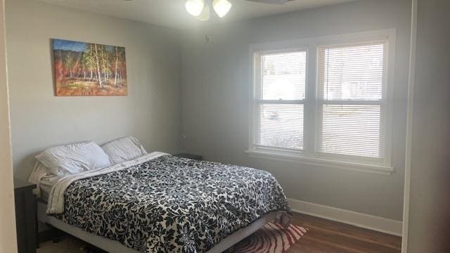 bedroom with ceiling fan, baseboards, multiple windows, and wood finished floors