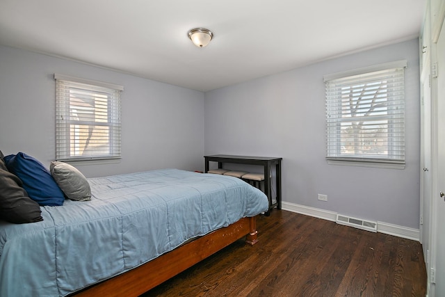 bedroom with wood finished floors, visible vents, and baseboards