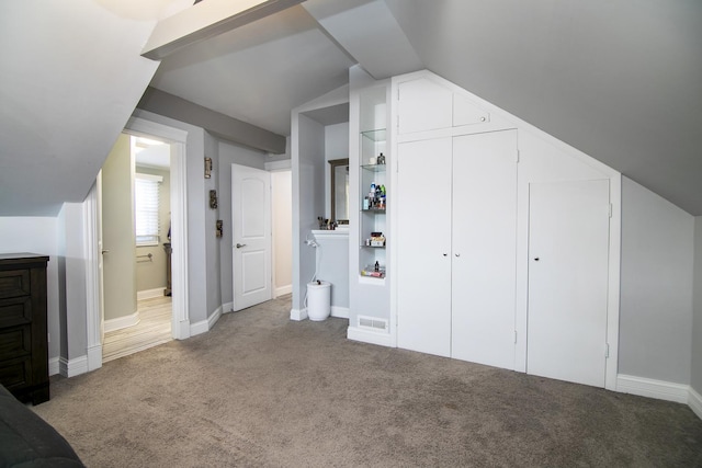 additional living space with vaulted ceiling, carpet, baseboards, and visible vents