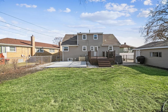 rear view of property featuring a wooden deck, a patio, a lawn, and a fenced backyard