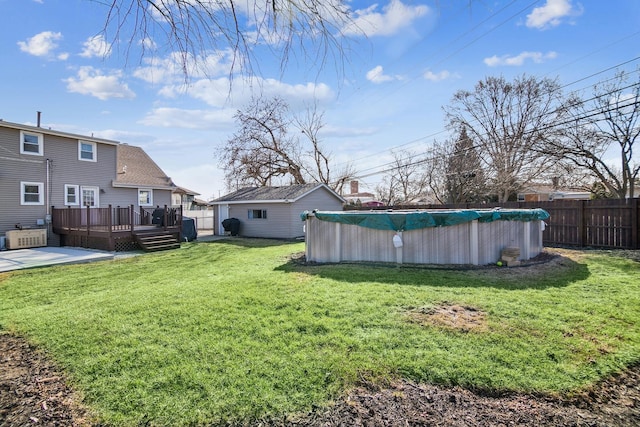 view of yard featuring a deck, an outbuilding, a fenced in pool, and fence