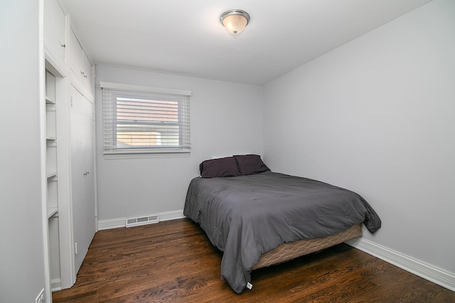 bedroom with wood finished floors, visible vents, and baseboards