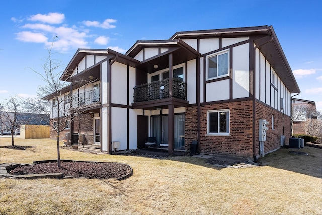 rear view of house featuring brick siding, stucco siding, cooling unit, and a balcony