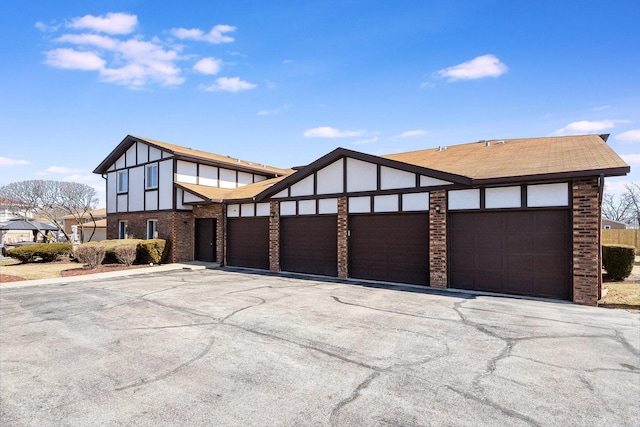 exterior space with brick siding, stucco siding, driveway, and a garage