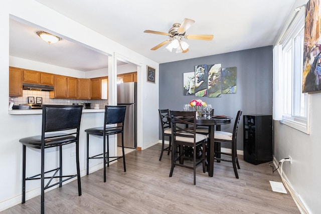 dining space featuring baseboards, light wood-style floors, and a ceiling fan