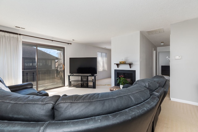 living area with a textured ceiling, plenty of natural light, visible vents, and light carpet